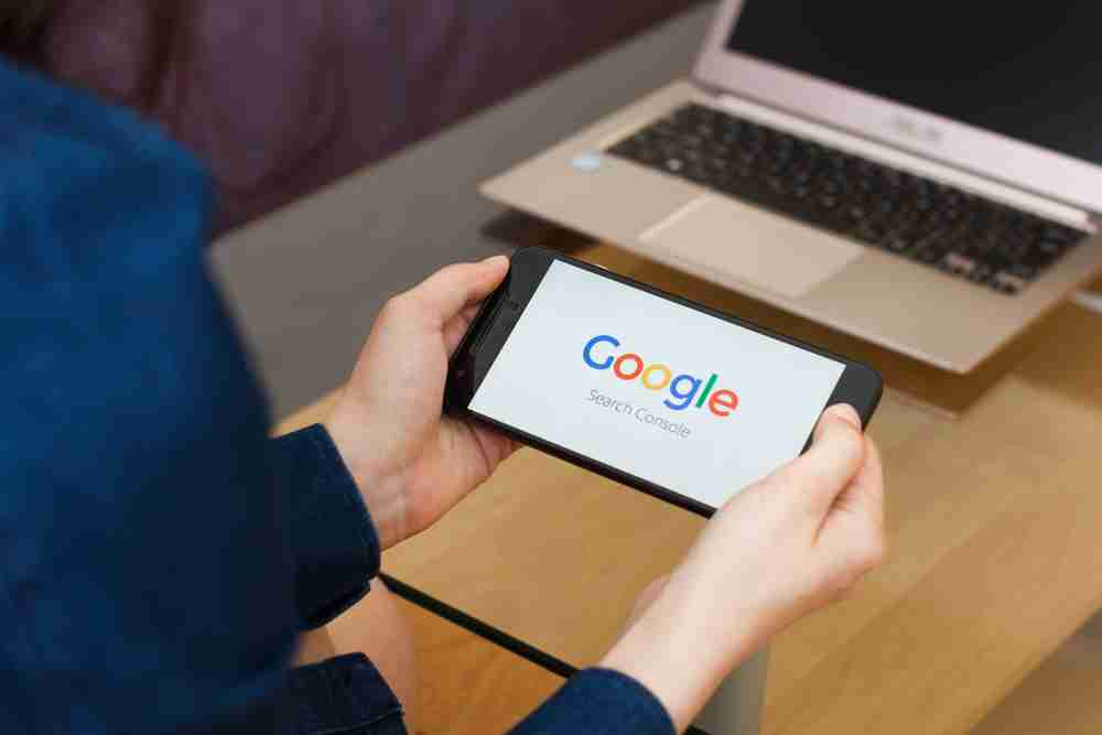 google search console, person holding a phone with google logo